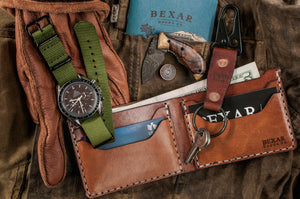 brown leather bifold with 4 card pockets and one cash sleeve next to leather keychain and watch