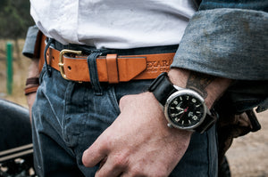 Adult male resting against motorcycle using a tan leather belt with brass buckle. Out of Focus watch strap with black leather strap