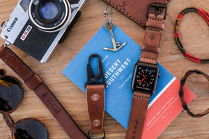 Whiskey cordovan and brown leather two pocket slim wallet next to keychain, bracelet, camera