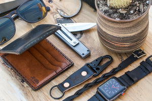 black cordovan leather exterior with brown cow leather interior two card pocket slim wallet next to keychain and watch strap