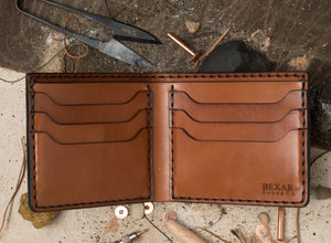 interior view of brown leather six pocket bifold wallet surrounded by materials used to make item