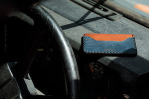 blue and brown leather two pocket slim wallet on top of vehicle dashboard