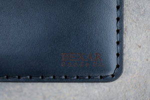 detail view of laser engraved Bexar logo on blue and brown leather notebook wallet with 4x4 journal book
