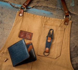 folded exterior view of blue and brown leather four card pocket bifold wallet on top of canvas apron