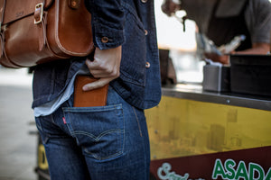 brown leather wallet being put into rear pocket of jeans