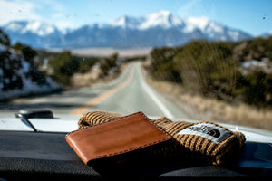 brown leather wallet on vehicle dashboard with mountain view in background