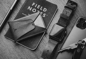 leather folding card wallet next to keychain and watch and phone