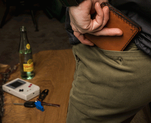 brown leather wallet being put into rear pocket of pants