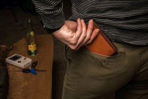 man putting brown leather wallet into rear pocket