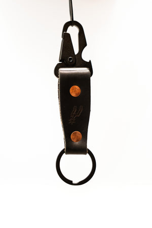 Black leather keychain with metal clip and copper accents on a white background