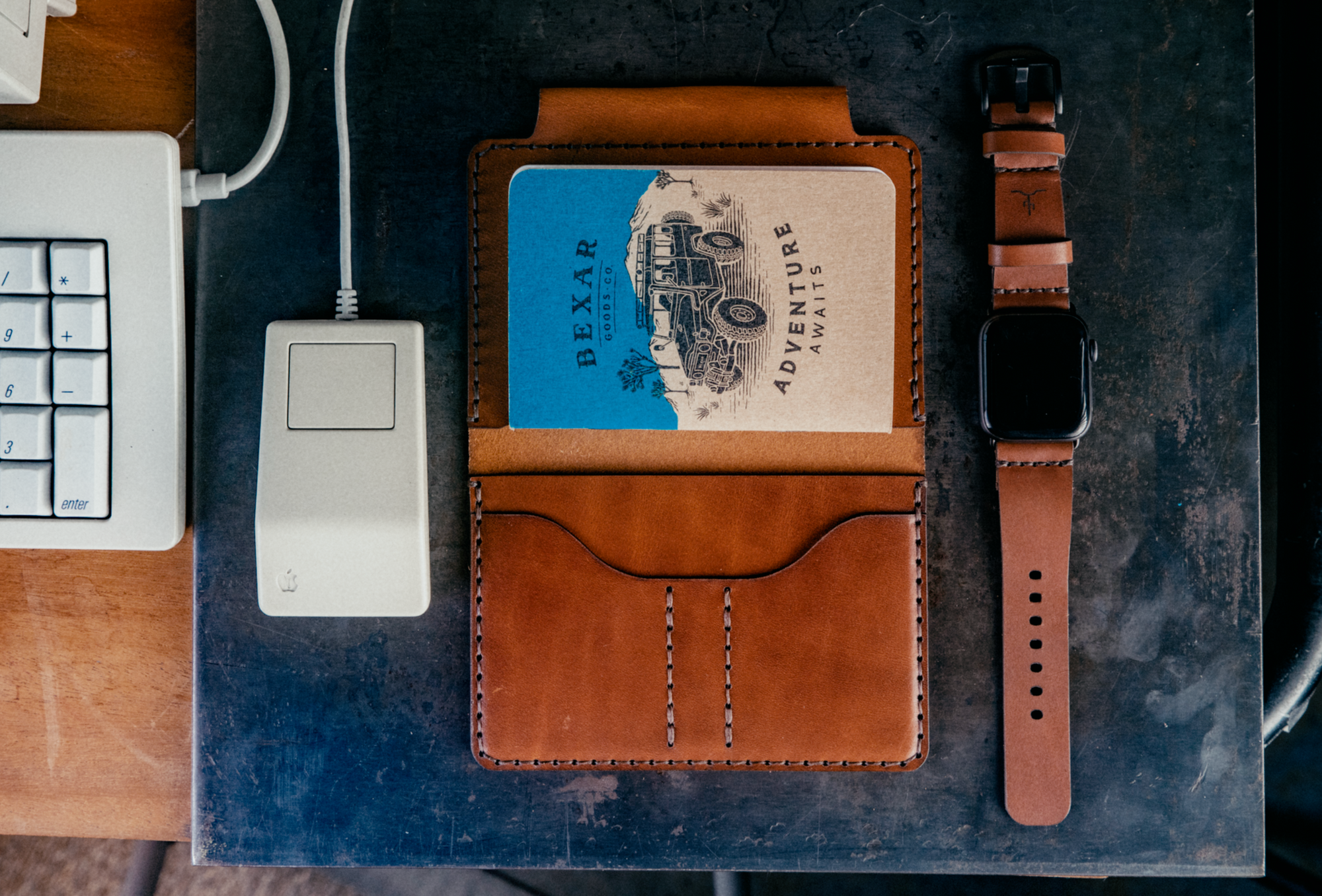 Field notes wallet and watch sitting on steel plate next to a retro computer mouse