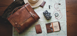  brown leather phone sleeve with card sleeve next to satchel and notebook wallet