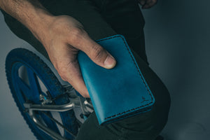 man holding blue exterior and brown interior leather wallet with four card pockets