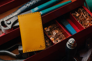 yellow leather exterior brown leather interior four pocket vertical wallet next to toolbox with leather tools