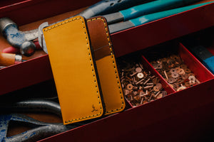 yellow leather exterior brown leather interior four pocket vertical wallet next to toolbox with leather tools
