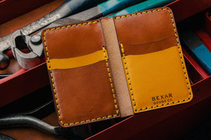 yellow leather exterior brown leather interior four pocket vertical wallet next to toolbox with leather tools