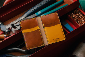 yellow leather exterior brown leather interior four pocket vertical wallet next to toolbox with leather tools