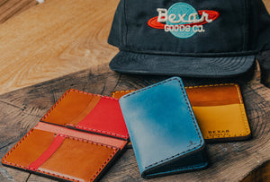 array of blue, yellow, red vertical four pocket leather wallets on wood block