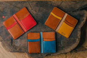 array of blue, yellow, red vertical four pocket leather wallets on wood block