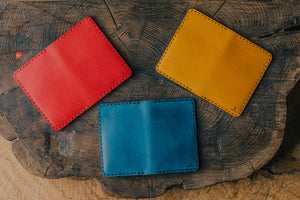 array of blue, yellow, red vertical four pocket leather wallets on wood block