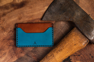 two pocket with one divider wallet shown in blue and brown leather next to axe