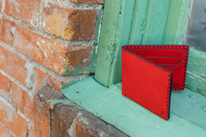 open view of red colored six pocket bifold next to a brick wall