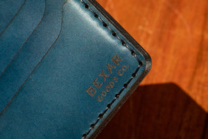 closeup of bexar goods engraved brand on inside pocket of blue bifold wallet 