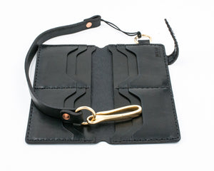 interior view of black leather eight pocket long wallet with two cash storage sleeves and brass lanyard