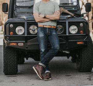 Adult male leaning on classic 4x4 featuring tan belt