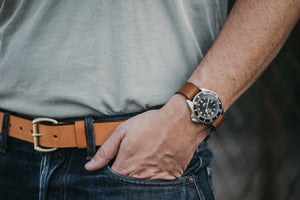 Adult male with hand in pocket emphasizing watch with leather watch strap