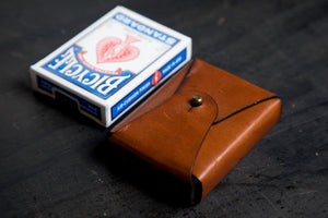 brown leather card carrying case  next to playing cards