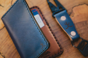 blue cordovan and brown leather four pocket vertical wallet next to keychain