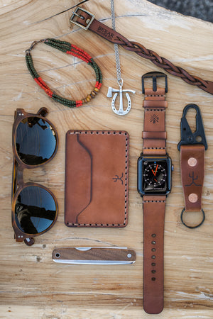 Whiskey cordovan and brown leather two pocket slim wallet next to watch, keychain, sunglasses