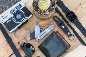 black cordovan leather exterior with black cow leather interior two card pocket slim wallet next to keychain and watch strap