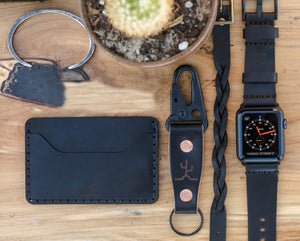 black cordovan leather exterior with black cow leather interior two card pocket slim wallet next to keychain and watch strap