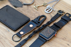 black cordovan leather exterior with black cow leather interior two card pocket slim wallet next to keychain and watch strap