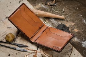interior view of brown leather bifold 4 pocket wallet surrounded by hand tools
