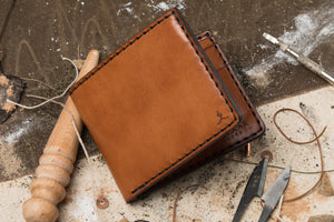 exterior view of brown leather bifold  4 pocket wallet surrounded by hand tools