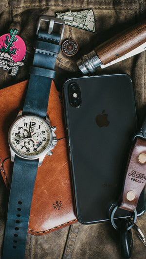 leather phone sleeve next to watch strap and keychain