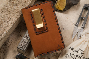 closed view brown leather four pocket vertical wallet with brass money clip on exterior