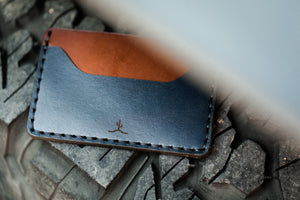 blue and brown leather two pocket slim wallet on top of 4x4 tire