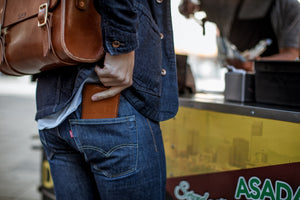 brown leather bifold wallet inserted into rear jean pocket