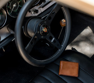 brown leather six card wallet sitting on sports car seat 