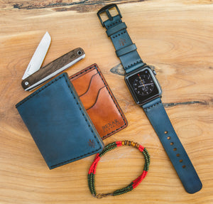 blue cordovan and brown leather six pocket bifold wallet next to matching watch strap