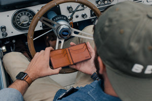 brown leather wallet with four card pockets opened to show interior inside a vehicle