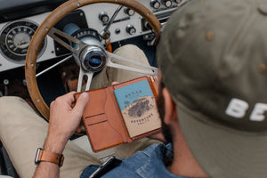  man holding brown leather notebook wallet with card sleeves and passport sleeve inside a 4x4 vehicle