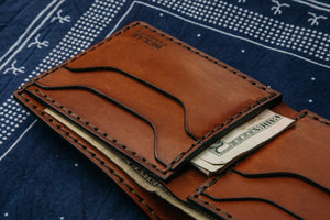 interior of brown four card pocket and two stash pockets with cash displayed on top of navy bandana