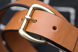 Macro detail of brass buckle on tan leather belt