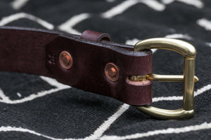 Macro shot of backside of dark brown leather belt showcasing hand hammered solid copper rivets