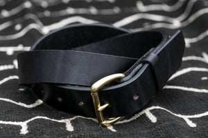 Black Leather Belt with brass bucke sitting on black blanket closeup